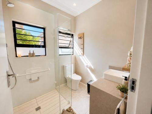 a bathroom with a shower and a sink and a toilet at Sandy Toes Home in Plettenberg Bay