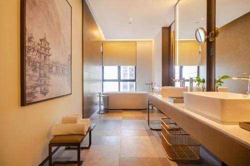 a bathroom with a row of sinks and a tub at Wanda JIN Baise in Qitang