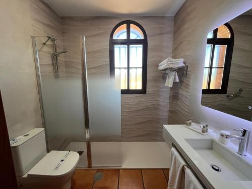 a bathroom with a shower and a toilet and a sink at Hotel Sierra de Ubrique in Ubrique