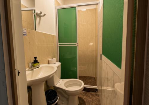 a bathroom with a toilet and a sink and a shower at Hotel Alcaraván Aguazul in Aguazul