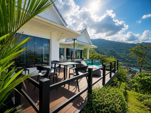 a house with a deck with a table and chairs at White Villa Lanta in Ko Lanta