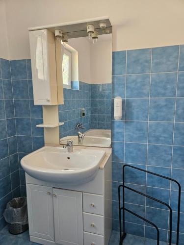 a bathroom with a sink and a mirror and blue tiles at B&B Eva in Ičići
