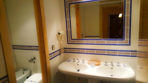 La salle de bains est pourvue d'un lavabo, d'un miroir et de toilettes. dans l'établissement Hotel Salvador, à Bailén