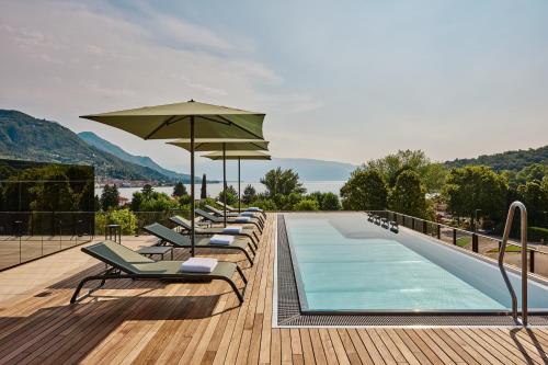 a row of lounge chairs next to a swimming pool at Falkensteiner Resort Lake Garda in Salò