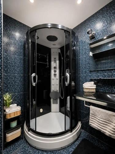 a shower in a bathroom with blue tiles at Medius Park Apartment in Sandanski