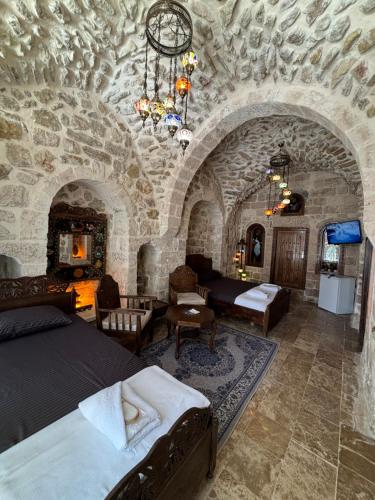 a bedroom with a stone wall with a bed and a living room at Kasri Reyyan in Mardin