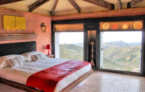 a bedroom with a large bed and large windows at Villa Borgo Musolino in Messina
