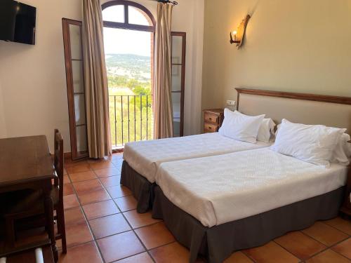 a bedroom with a bed and a large window at Hotel Sierra de Ubrique in Ubrique