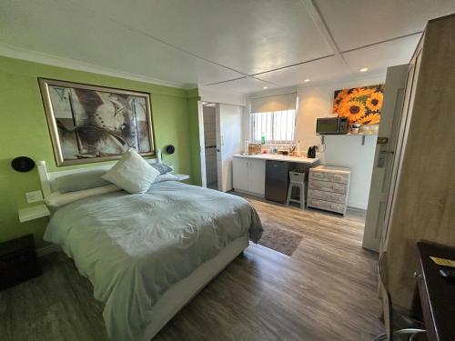 a bedroom with a large bed and a kitchen at Tiny Treasure in Klein Silwermyn