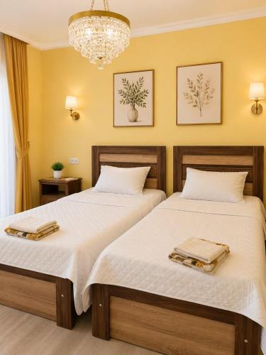 two beds in a room with yellow walls and a chandelier at Four seasons in Kutaisi