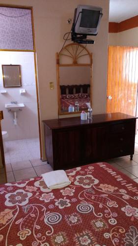a bathroom with a bed with a mirror and a television at Hotel y Bungalows Olivares in Acapulco