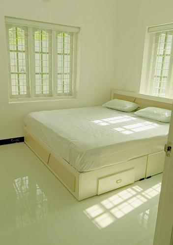 a bed in a white room with windows at White Cloud Stay Attappadi in Agali