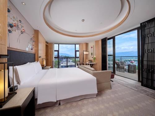a bedroom with a large white bed and a large window at Hilton Dali Resort & Spa in Dali