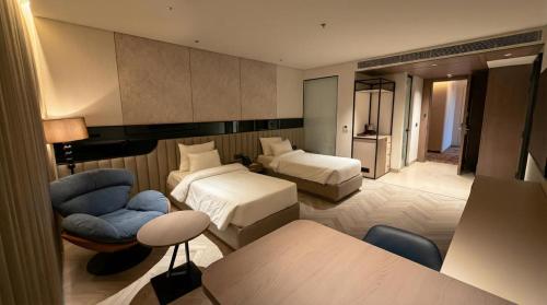 a hotel room with two beds and a chair at Lumeirrah Suites in Moga