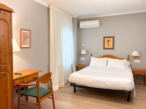 a bedroom with a bed and a desk and a chair at Hostal Restaurant Roma in Cubells