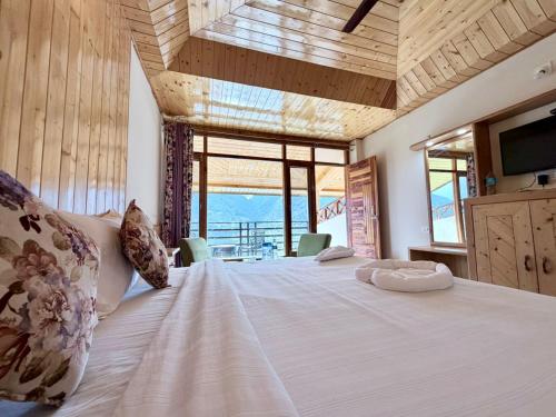 a bedroom with a large bed with a large window at Hotel Mount Manali - The Cozy Stay in Vashisht