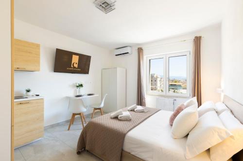 a white bedroom with a bed and a table at Comfyrooms in Quartu SantʼElena