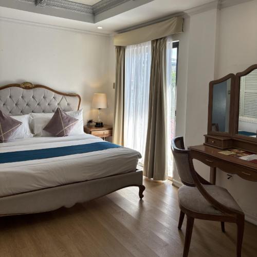 a bedroom with a bed and a desk and a television at Queen Margarette Hotel in Silañgang Isabang