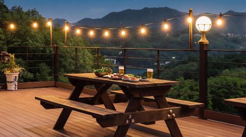 a wooden table and bench on a deck with lights at Gapyeong Art Pension in Gapyeong