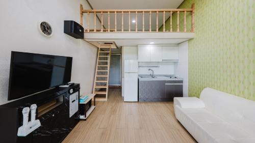 a living room with a couch and a tv and a kitchen at Gapyeong Art Pension in Gapyeong