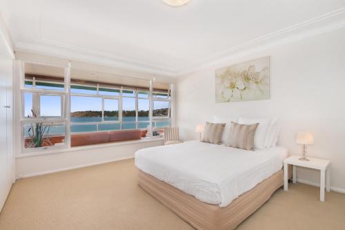a white bedroom with a large bed and a window at The Oriana in Sydney