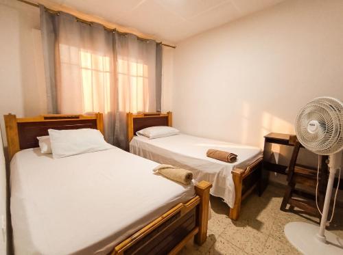 a bedroom with two beds and a fan at Hostal, casa Jaramillo in Roldanillo