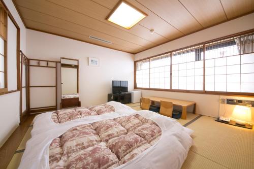 a bedroom with a large bed and two windows at Yokaichi Royal Hotel in Yōkaichi