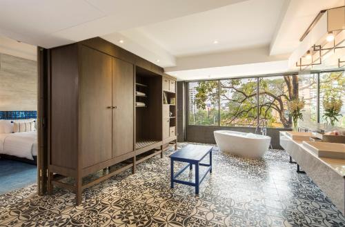a bathroom with a tub and a sink and a bed at U Nimman Chiang Mai in Chiang Mai