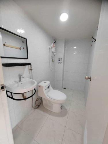a white bathroom with a toilet and a sink at Erawan Place in Mae Sot