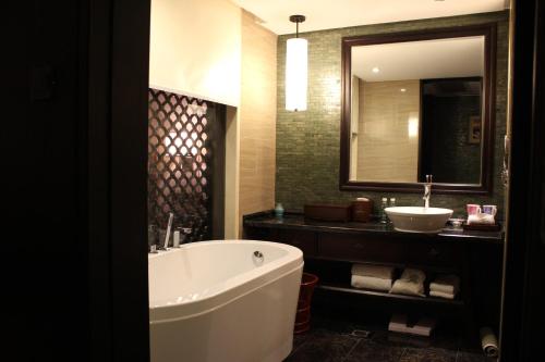 a bathroom with a tub and a sink and a mirror at Xiang Yun Sha Garden Hotel Shunde in Shunde