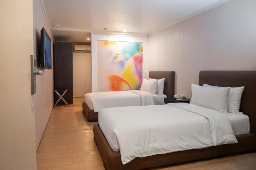 a hotel room with two beds and a painting on the wall at Green Sun Hotel in Manila