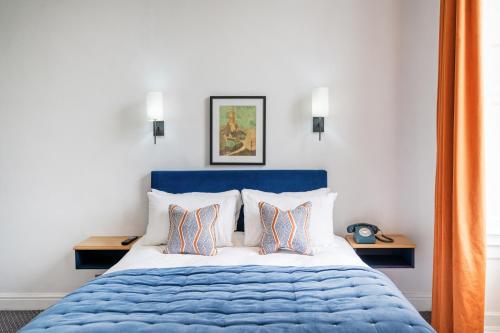 a bedroom with a blue and white bed with two pillows at The Rodney Hotel in Bristol