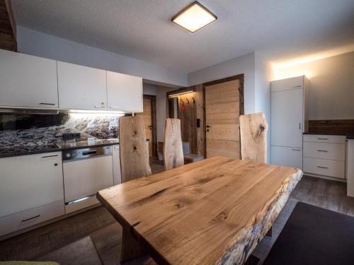 a kitchen with white cabinets and a wooden table at Hotel & Apart Central in Fügen