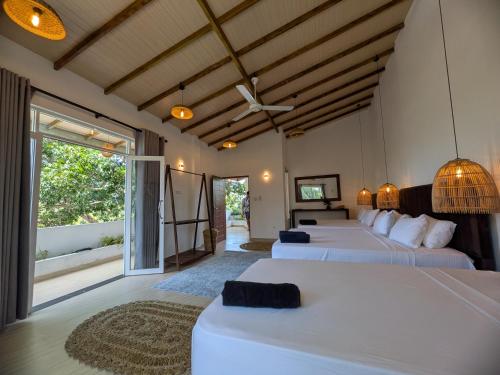 a bedroom with three beds and a large window at Casa Luna Home Stay in Dickwella