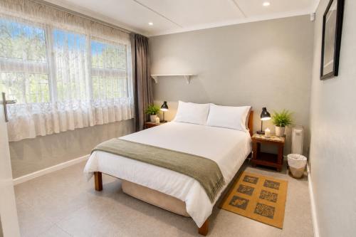 a bedroom with a large white bed and a window at Sandy Fingers Apartment in Plettenberg Bay