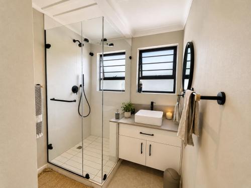 a bathroom with a glass shower and a sink at Sandy Fingers Apartment in Plettenberg Bay