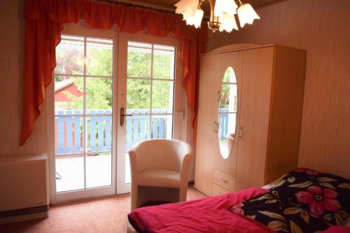 a bedroom with a bed and a chair and a window at Ferienwohnung Am oberen Hexenstieg in Altenbrak