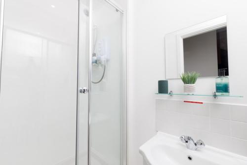 a white bathroom with a shower and a sink at Mowbray's Nook, Shetland Islands in Lerwick