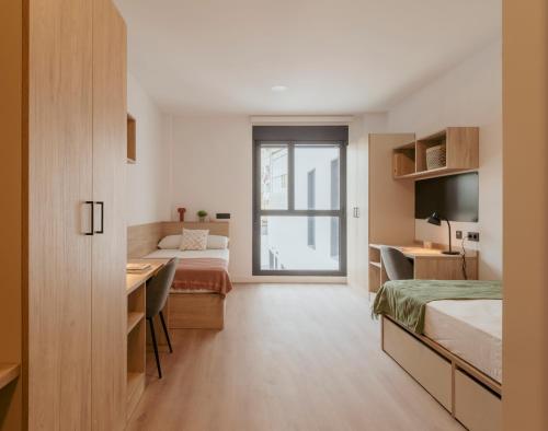 a bedroom with two beds and a desk and a television at micampus Logroño Centro in Logroño
