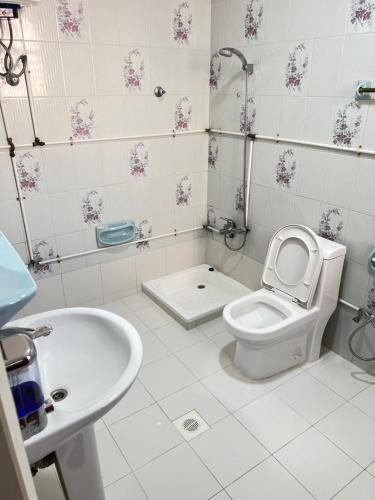 a white bathroom with a toilet and a sink at Waterfront vip master room in Muscat