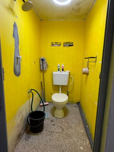 a bathroom with a toilet in a yellow wall at Dahlia Roomstay Jelai in Gemas