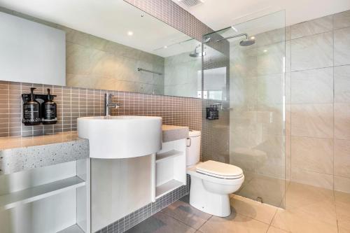 a bathroom with a toilet and a sink and a shower at 18th Floor Seaview Executive Style King Bed with Pool and Gym in Darwin
