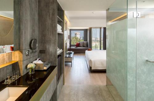 a bathroom with a shower and a bed in a room at U Nimman Chiang Mai in Chiang Mai