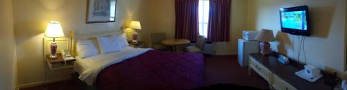 a hotel room with a bed and a flat screen tv at Port Motel in Port Colborne