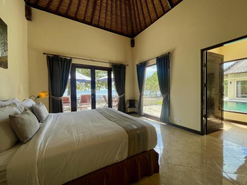 a bedroom with a bed and a large window at Starsand Beach Resort in Sekotong
