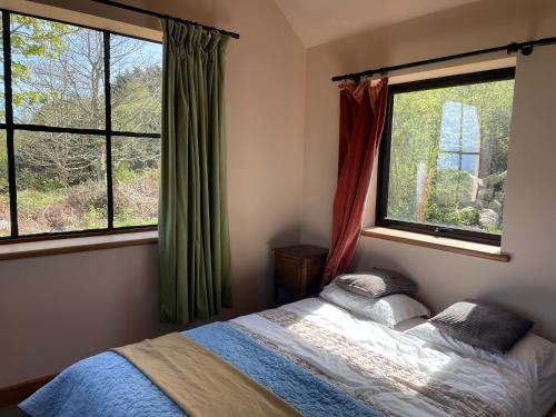 a bedroom with a bed and two windows at The Quarry Caravan in Falmouth