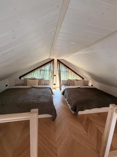two beds in a room with two windows at Meža māja in Ģipka