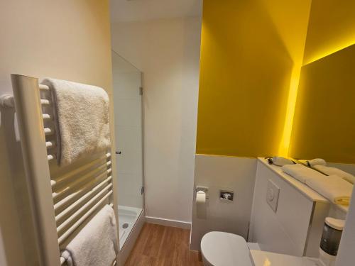 a bathroom with a toilet and a yellow wall at my MINGA Airport serviced Apartments in Hallbergmoos