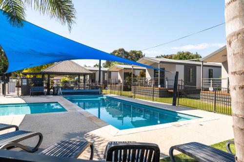 a swimming pool with chairs and a blue umbrella over it at Geelong Holiday Park in Geelong