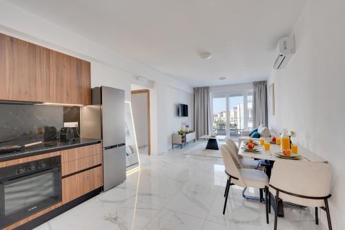 a kitchen and living room with a table and chairs at Oasis Luxury Residence B101 - Pool View in Xylophaghou